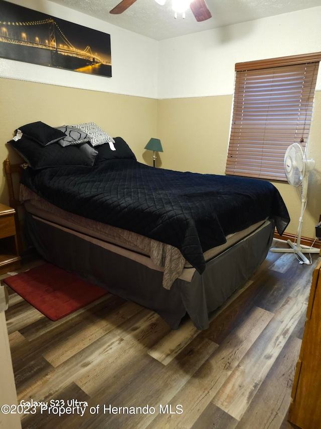 bedroom with wood-type flooring, ceiling fan, and a textured ceiling