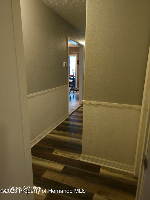 hall with a textured ceiling and dark hardwood / wood-style floors