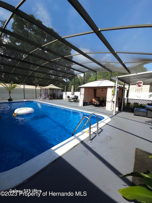 view of pool featuring glass enclosure and a patio