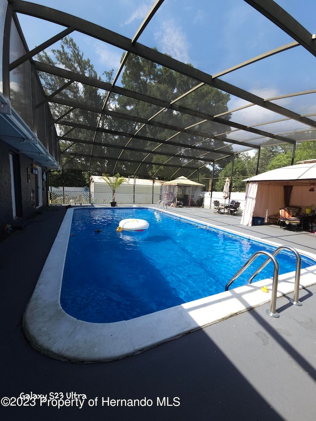 view of swimming pool featuring a lanai and a patio area