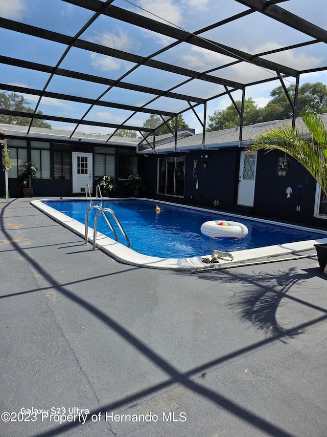 view of swimming pool featuring a patio and glass enclosure