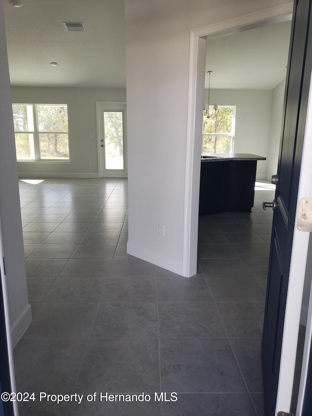 hallway featuring a wealth of natural light and dark tile patterned floors