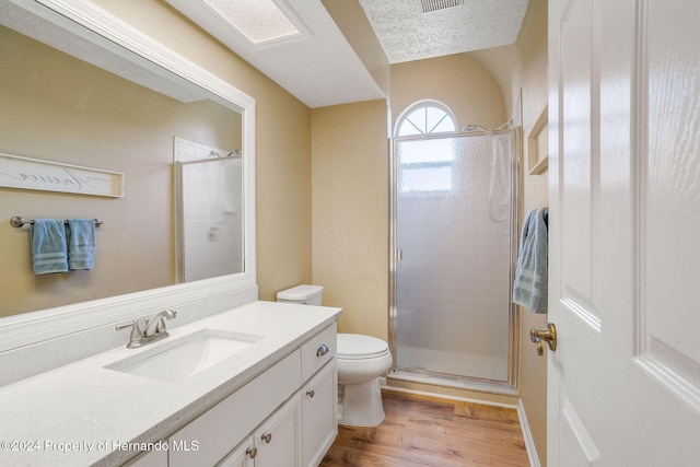 bathroom featuring an enclosed shower, toilet, wood-type flooring, a textured ceiling, and vanity