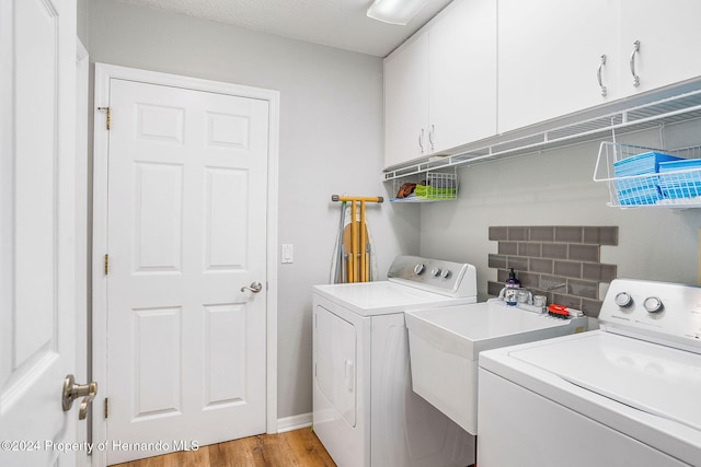 laundry room with sink, light hardwood / wood-style floors, separate washer and dryer, and cabinets