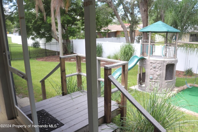 wooden terrace featuring a playground and a lawn