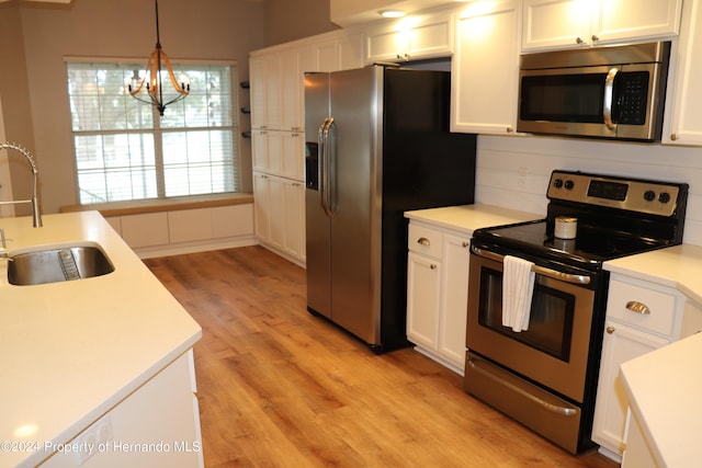 kitchen featuring stainless steel appliances, sink, pendant lighting, light hardwood / wood-style flooring, and white cabinetry