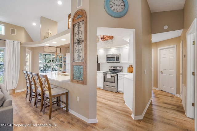 kitchen with appliances with stainless steel finishes, light hardwood / wood-style flooring, and white cabinets