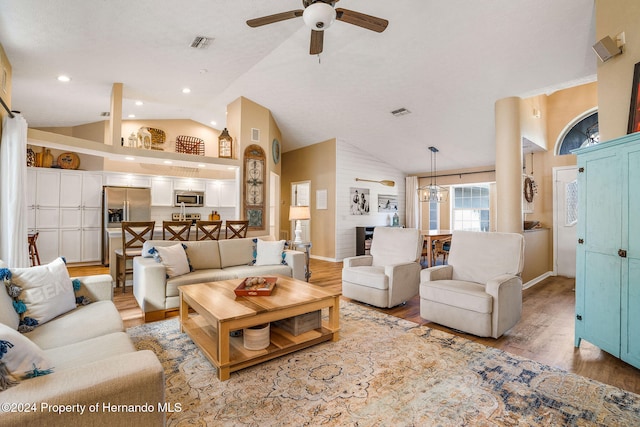 living room with ceiling fan, vaulted ceiling, and light hardwood / wood-style floors