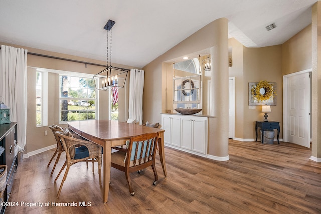 dining area with hardwood / wood-style flooring, high vaulted ceiling, and a notable chandelier