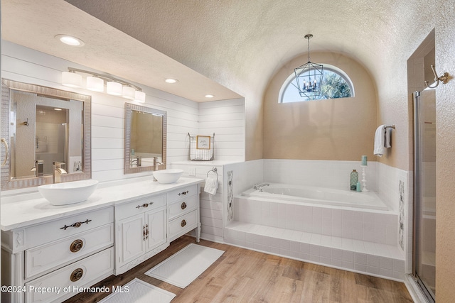 bathroom featuring independent shower and bath, wood-type flooring, vanity, and a textured ceiling