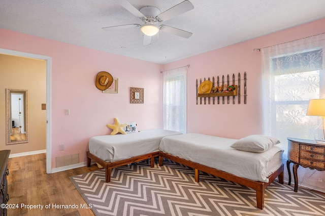 bedroom with ceiling fan, wood-type flooring, and a textured ceiling