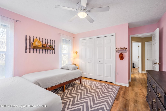 bedroom featuring ceiling fan, a closet, dark hardwood / wood-style flooring, and a textured ceiling