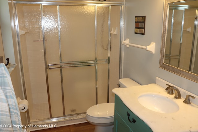 bathroom with hardwood / wood-style flooring, toilet, vanity, and an enclosed shower