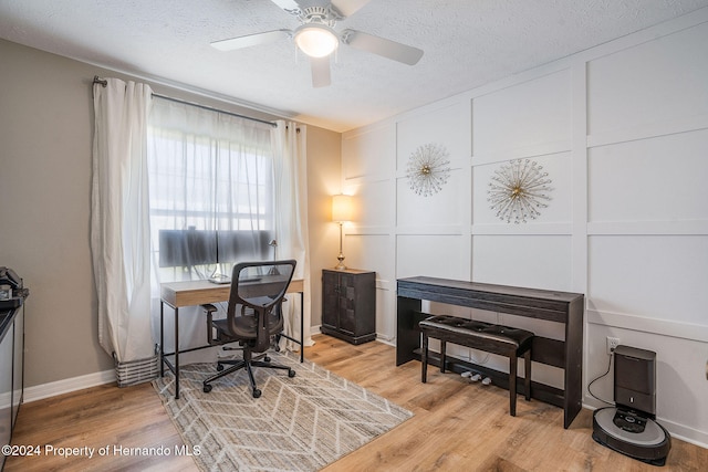 office area with a textured ceiling, ceiling fan, and light hardwood / wood-style flooring