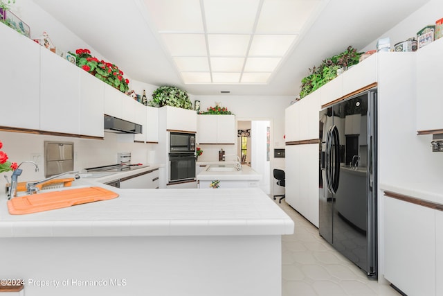 kitchen featuring white cabinets, black appliances, and exhaust hood