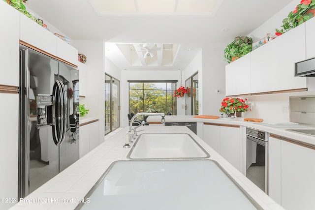11915 W Riverhaven Dr, Homosassa, FL 34448 - kitchen with black fridge with ice dispenser, light countertops, a sink, and white cabinets