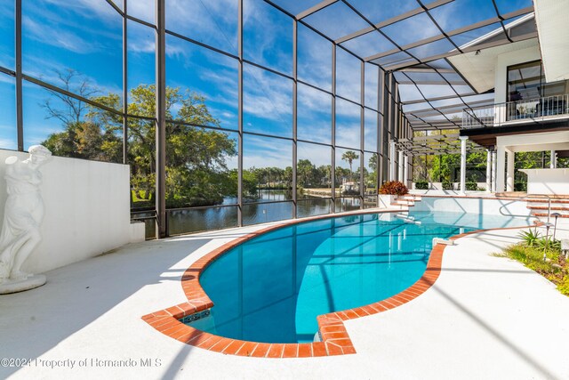 view of pool featuring a lanai, a water view, and a patio area