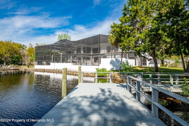 view of dock with glass enclosure and a water view