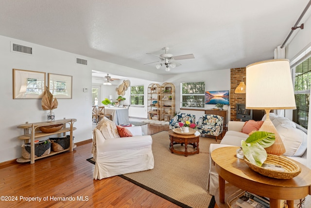 living room with hardwood / wood-style flooring, ceiling fan, and a fireplace