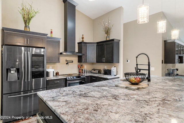 kitchen featuring light stone counters, stainless steel appliances, wall chimney range hood, dark brown cabinetry, and pendant lighting