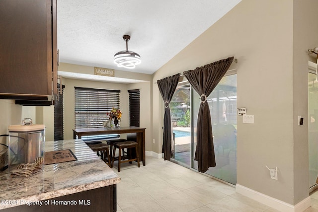 tiled dining room featuring lofted ceiling and a textured ceiling