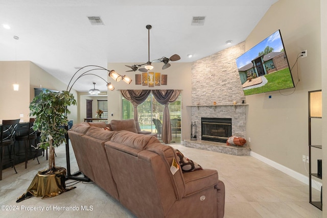 living room with a stone fireplace, light tile patterned floors, ceiling fan, and a towering ceiling