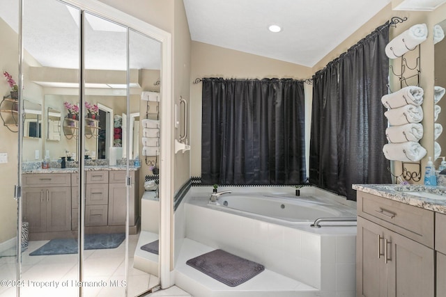 bathroom featuring vanity, tile patterned flooring, lofted ceiling, and tiled tub