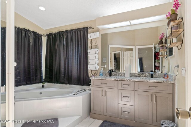 bathroom with tile patterned flooring, vanity, tiled tub, and vaulted ceiling