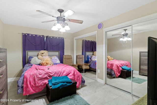 bedroom with a textured ceiling, multiple closets, and ceiling fan