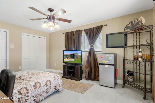 bedroom with ceiling fan, stainless steel refrigerator, and a closet