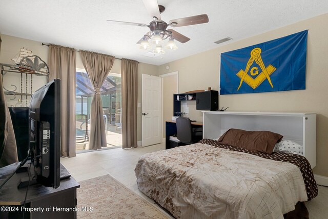 bedroom with ceiling fan, light tile patterned flooring, access to exterior, and a textured ceiling