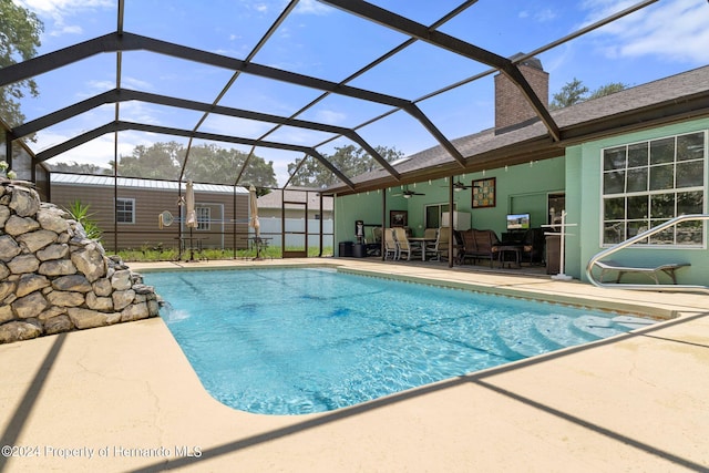 view of pool with a lanai, ceiling fan, pool water feature, and a patio area