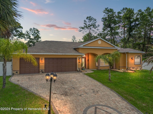 single story home featuring a garage and a yard