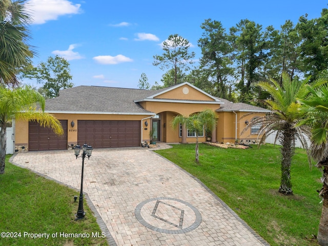 ranch-style home with a garage and a front lawn