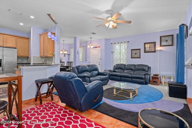 living room with light tile patterned flooring and ceiling fan with notable chandelier