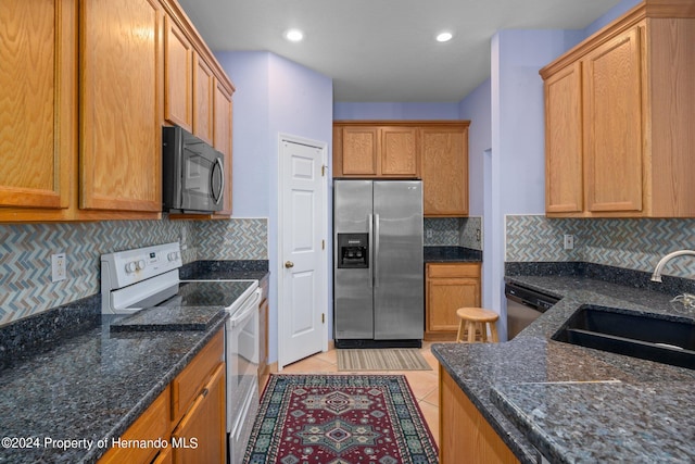 kitchen with dark stone countertops, light tile patterned floors, backsplash, and appliances with stainless steel finishes