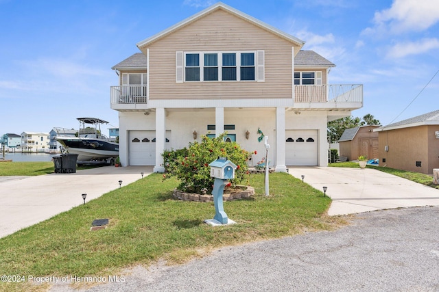 view of front property featuring a garage, a front lawn, and a balcony