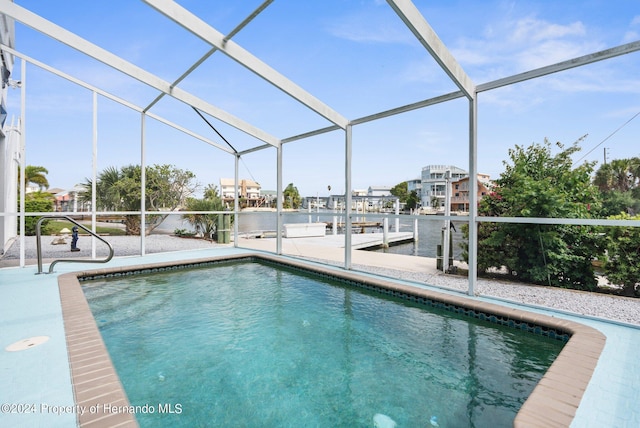 view of swimming pool featuring glass enclosure, a patio area, a water view, and a boat dock