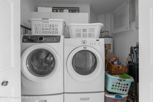 washroom with washing machine and dryer, water heater, and a textured ceiling