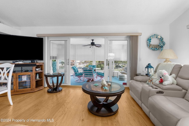 living room with ceiling fan, wood-type flooring, and a textured ceiling