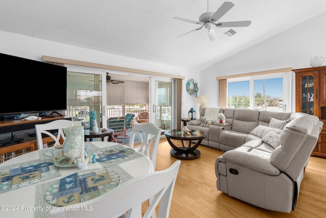 living room with light wood-type flooring, lofted ceiling, a textured ceiling, and ceiling fan