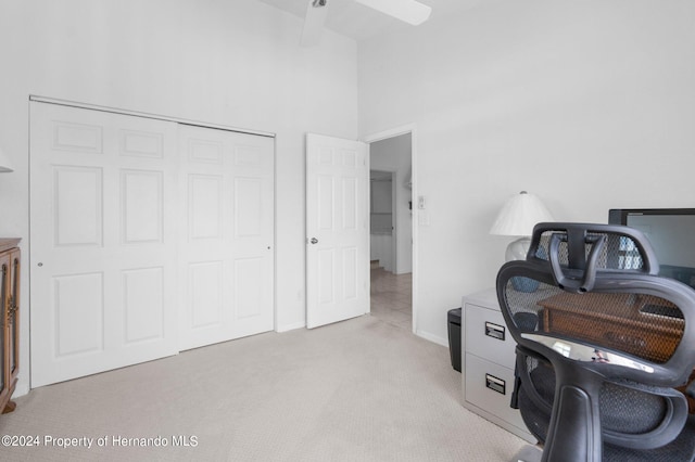 office area featuring light colored carpet, ceiling fan, and a towering ceiling