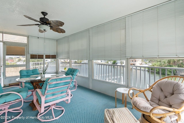 sunroom featuring a water view and ceiling fan