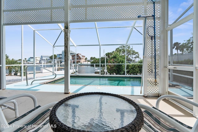 view of swimming pool featuring a patio, glass enclosure, and a water view