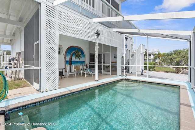 view of pool with glass enclosure and a patio area