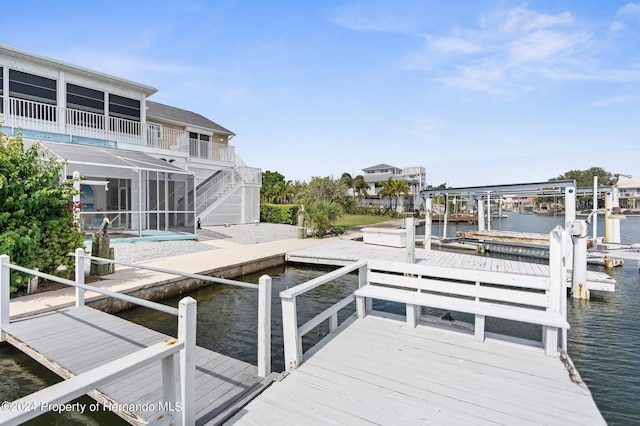 view of dock featuring a water view, a patio area, a balcony, and a pool