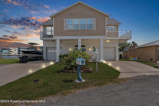 view of front of home with a garage, a lawn, and a balcony