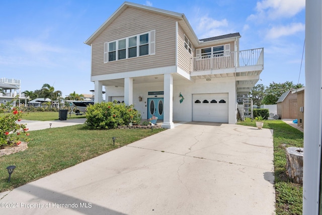 view of front of home with a garage, a front yard, and a balcony