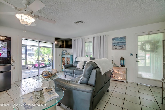 tiled living room with ceiling fan and a textured ceiling