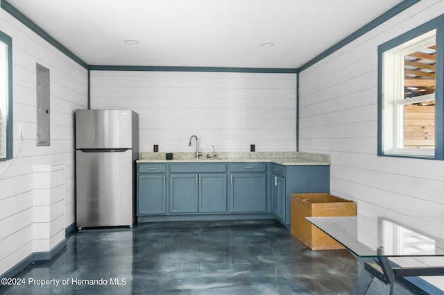 kitchen with electric panel, wooden walls, sink, and stainless steel fridge